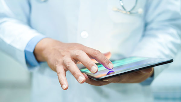 A male doctor is using a tablet device.